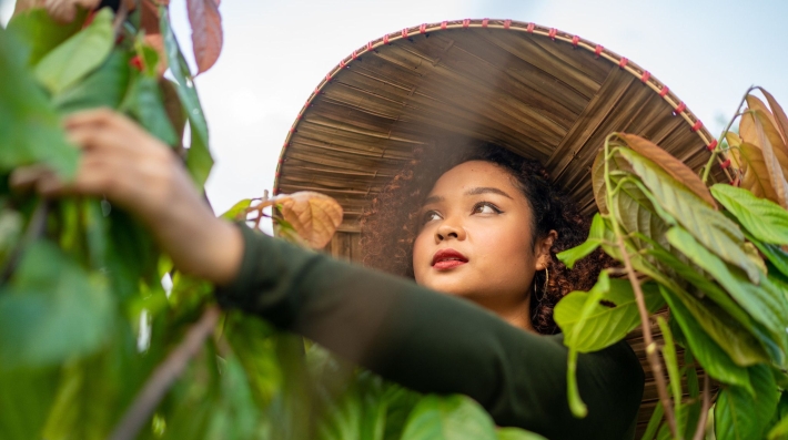 A young woman tends to a cacao plant in the Philippines as part of a project to combat deforestation.